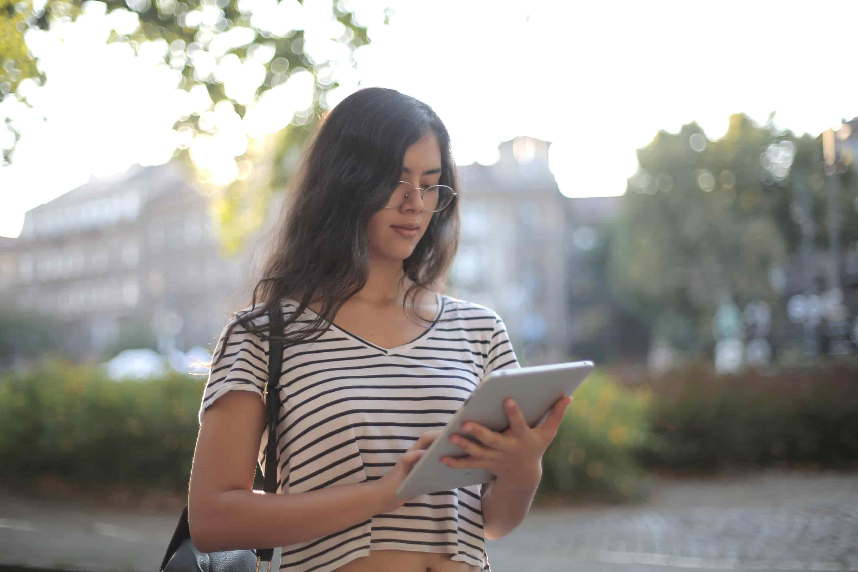  A photo of a Latina woman with glasses, using a tablet 